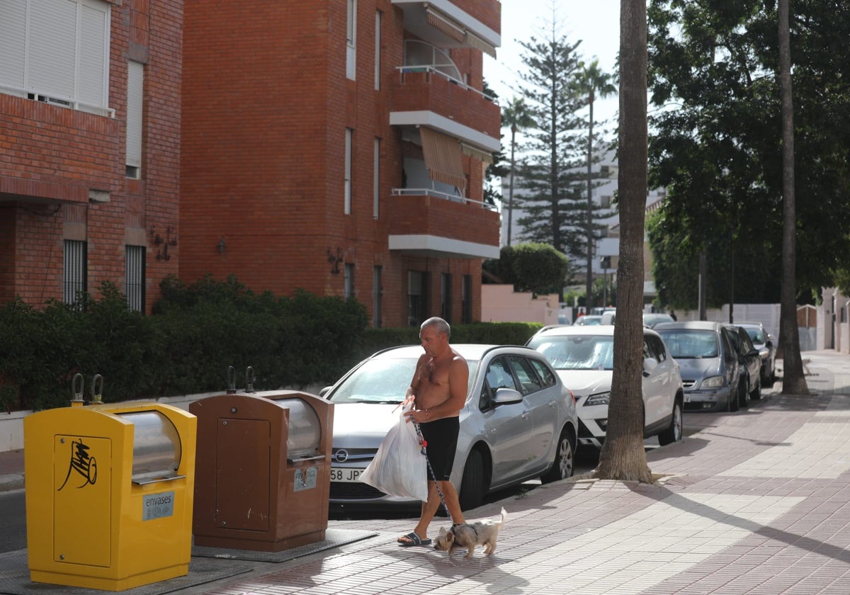 Un hombre, a punto de depositar basura en un contenedor en Rota