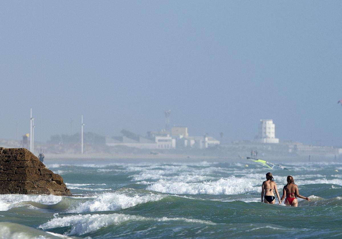 Bañistas cruzando la playa de Cortadura a la altura de la residencia militar