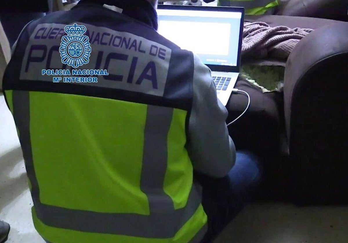 Un agente de la Policía Nacional examina un ordenador incautado en una operación contra ciberdelincuentes.