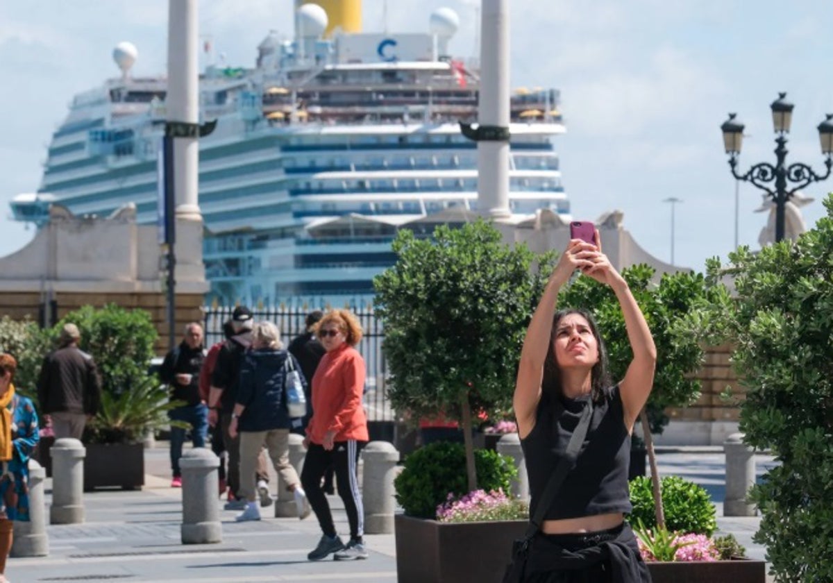 Una turista fotografía la ciudad con un crucero al fondo.