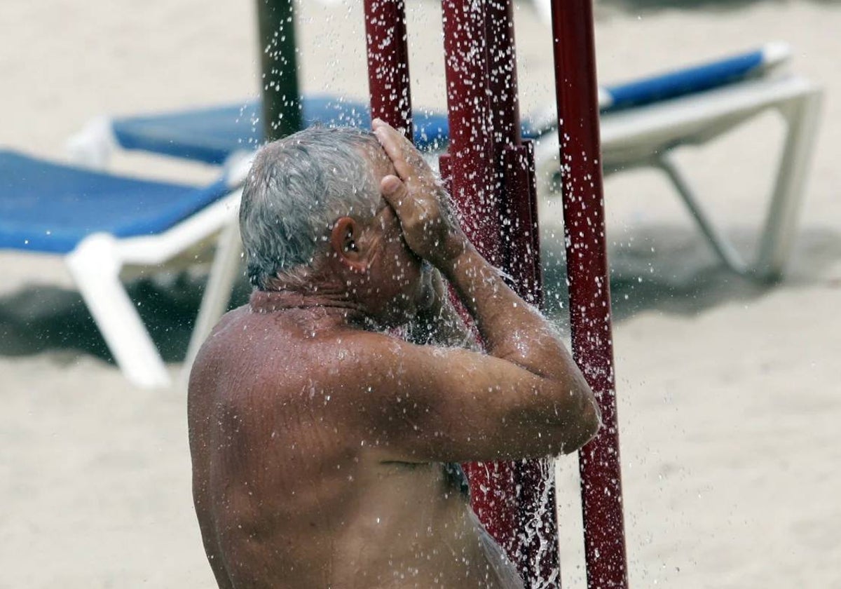 Un hombre utiliza una de las duchas en las playas de Cádiz