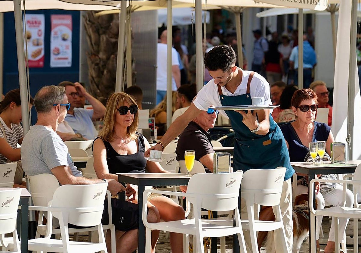 Una camarero atiende a unos turistas en un bar en Cádiz