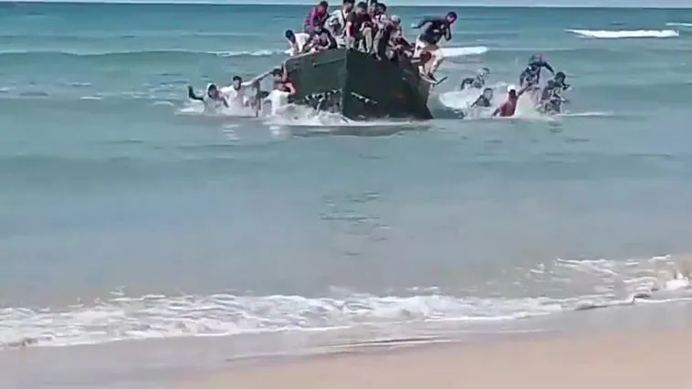 Una patera atestada de inmigrantes llega a la playa de Cádiz ante la incrédula mirada de los bañistas