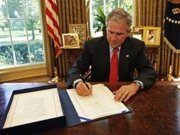 El presidente Bush firma el texto en el despacho oval./ AP