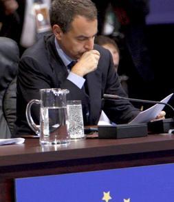 Zapatero está sentado junto a Solbes sobre una bandera de la Unión Europea. /AP