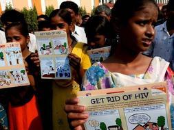 Varias chicas indias llevan carteles sobre el sida en la estación de tren de Sealdha, durante la celebración de una campaña de prevención de sida en Calcuta (India)./ Archivo