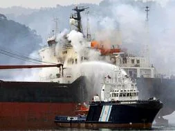 Una embarcación de Salvamento Marítimo arroja agua sobre el mercante 'Doxa', de bandera chipriota. / Efe