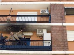 Un integrante del cuerpo judicial señala la ventana del quinto piso desde la que ha caído el bebé. / Efe.