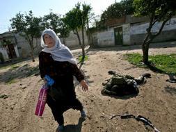 Una mujer de Gaza se aleja del cadáver de un miliciano abatido. / Efe