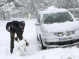 Un conductor intenta liberar su coche de la nevada en la zona del puerto de Navacerrada en Madrid, comunidad afectada por el fuerte temporal de nieve. / Efe