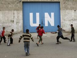 Unos niños juegan al fútbol frente a un almacén de Naciones Unidas en Ciudad de Gaza./ Efe