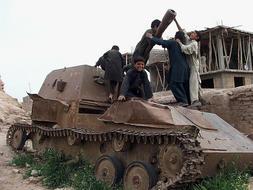 Un grupo de niños afganos juegan sobre un tanque ruso abandonado en una de las carreteras de Herat./ Afp