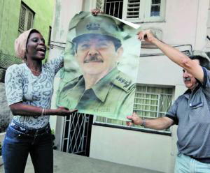 Dos entusiastas del régimen cubano sostienen un cartel con la figura de Raúl Castro / REUTERS