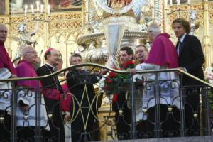 Autoridades eclesiásticas y atléticos alzan la copa de la UEFA ante la imagen de la Virgen