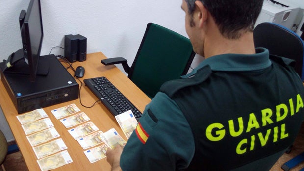 Un agente comprueba la falsedad de los billetes