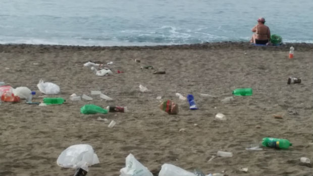 Bañistas junto a la basura en la playa de La Malagueta
