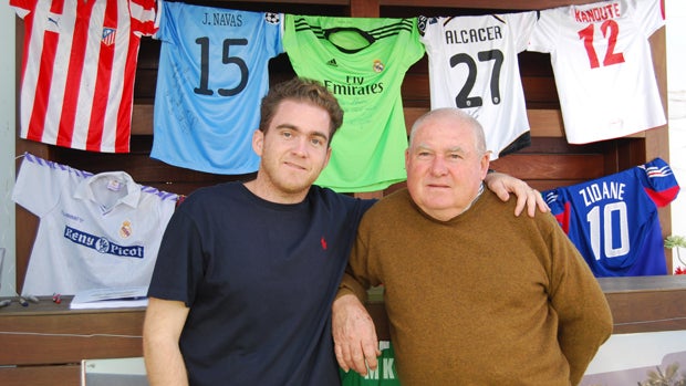 Carlos posa con su padre durante una exposición de sus camisetas