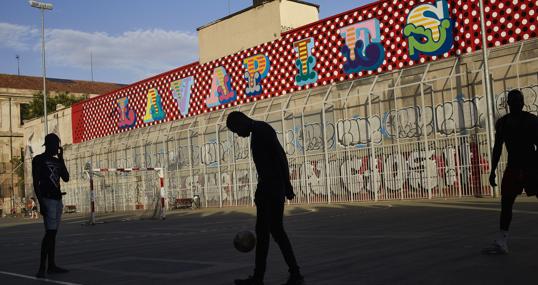 Varios jóvenes juegan al fútbol en unas pistas de Lavapiés