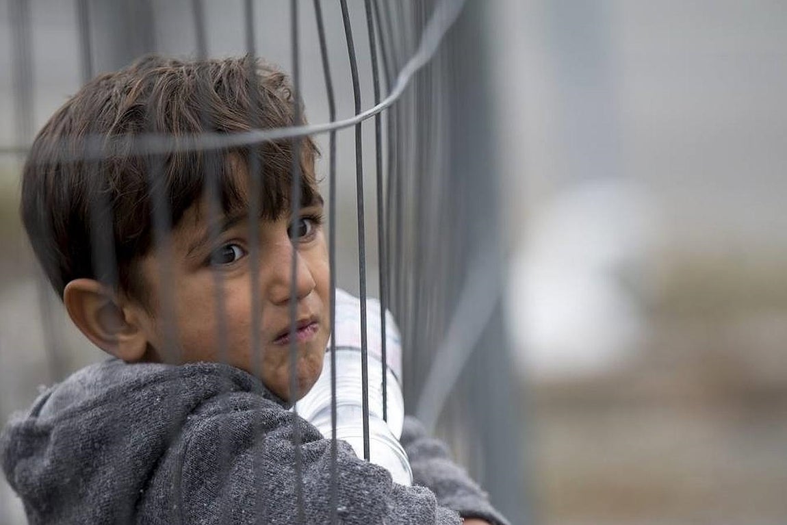 Un niño aguarda tras la verja para cruzar la frontera entre Austria y Eslovenia en la ciudad de Spielfeld, en la región austriaca de Estiria. 