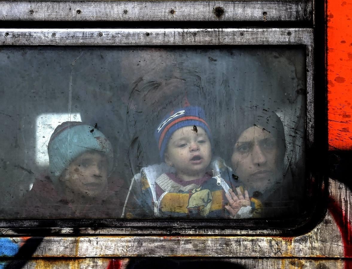 Una familia de refugiados mira a través de la ventana del tren antes de partir hacia la frontera serbia desde Macedonia 