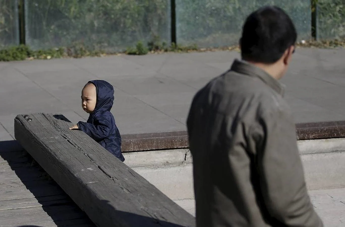 Un hombre observa jugar a su nieto en Beijing
