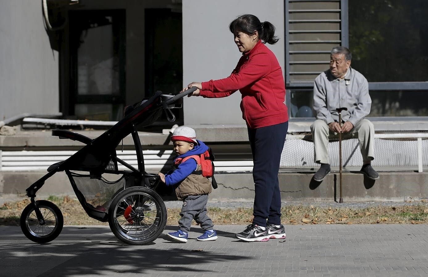 Una mujer y su nieto pasean por la calle en una zona residencial de Beijing