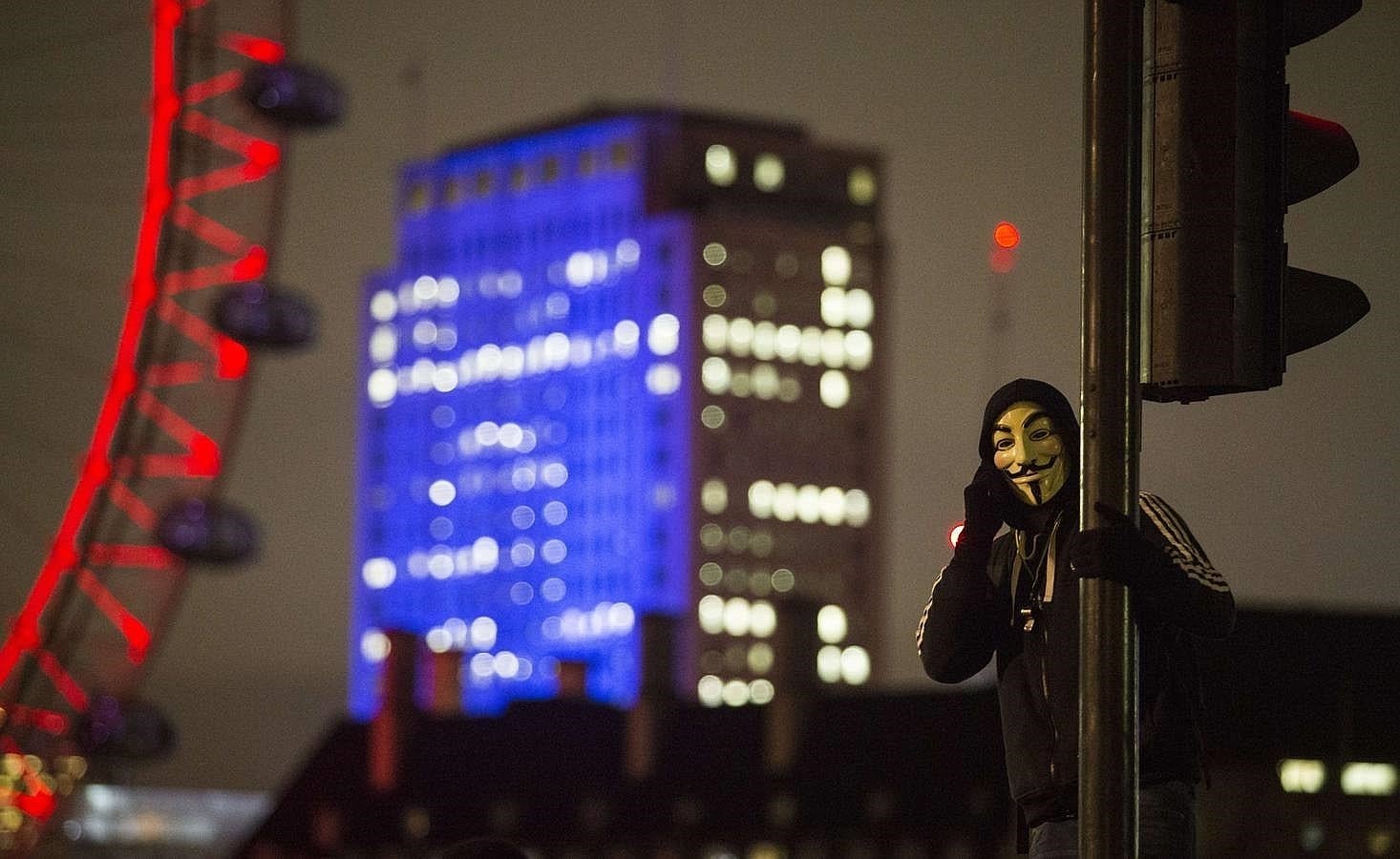 Un simpatizante de «Anonymous» habla por teléfono junto al London Eye, durante la manifestación de este jueves en Londres. 