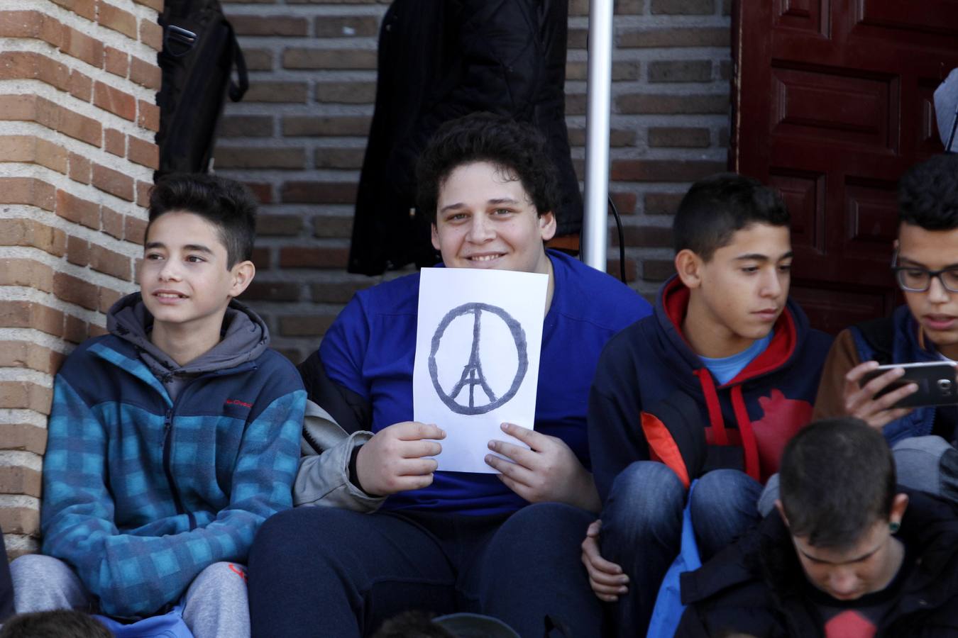 Los estudiantes han tomado asiento portando cartulinas con uno de los símbolos que más ha circulado estos días por las redes sociales, el de la torre Eiffel encuadrada en el símbolo de la paz. 