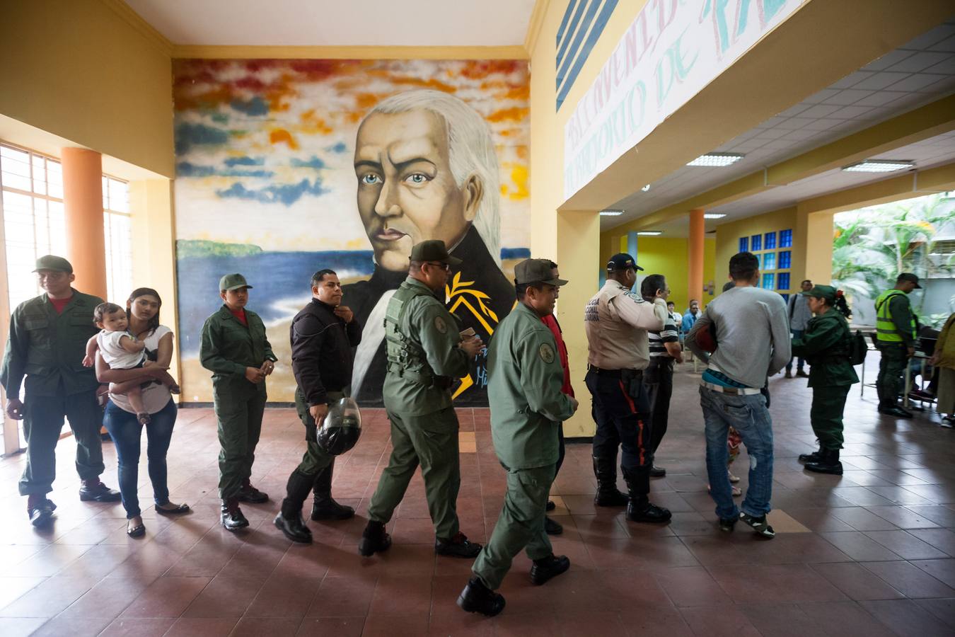 Un grupo de personas hace fila a la entrada de un centro de votación. 