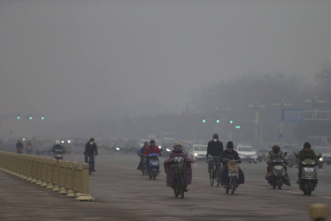 Motoristas y ciclistas usa mascarillas para protegerse de la contaminación mientras circulan por una calle de Pekín (China)