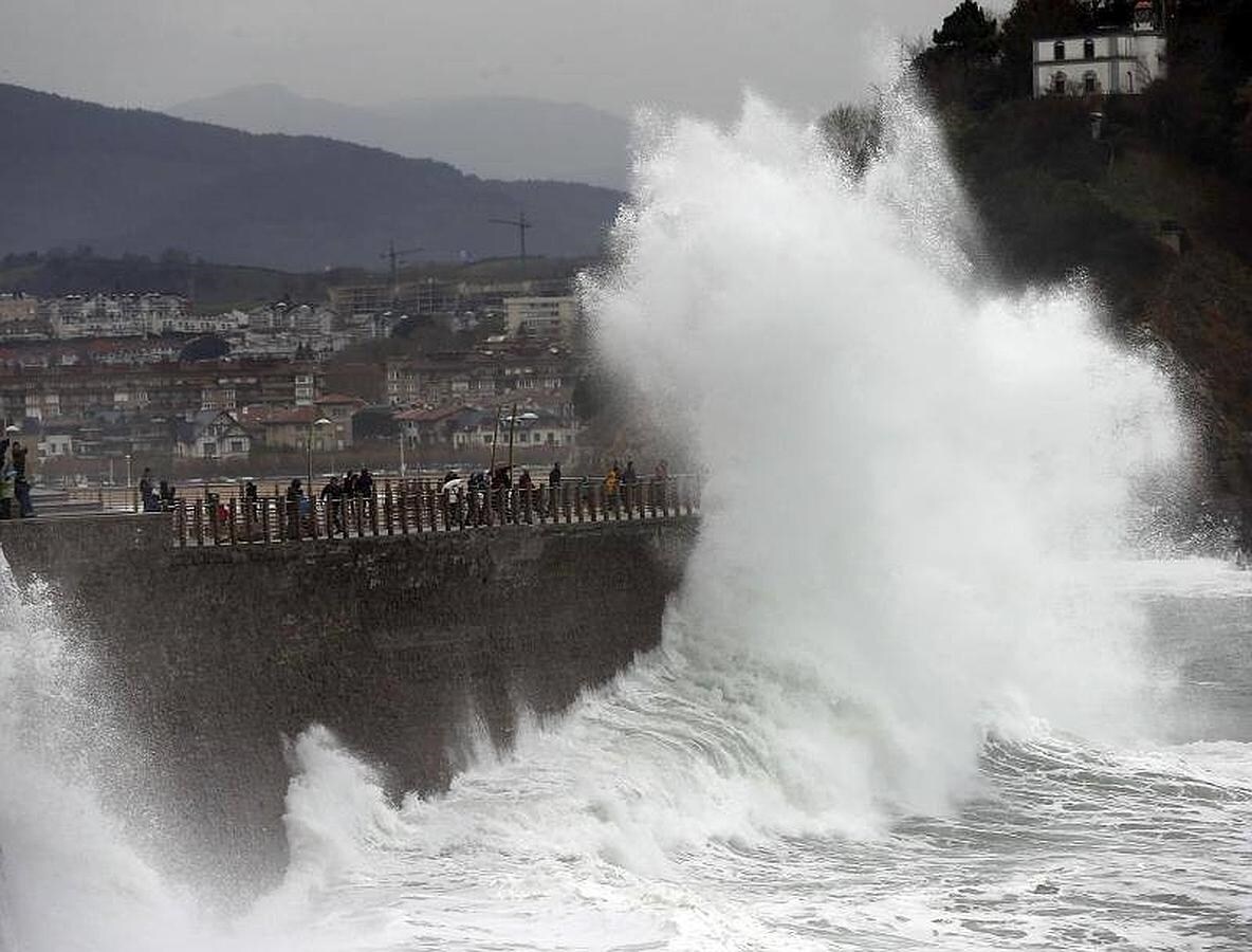 Varias personas huyen de una ola en el Paseo Nuevo de San Sebastián, hoy cerrado al tráfico, donde se ha decretado la alerta naranja por fenómenos costeros