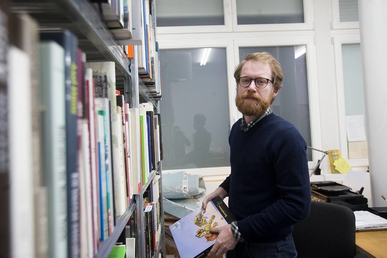 Vassallo consulta algunos títulos de su librería. 