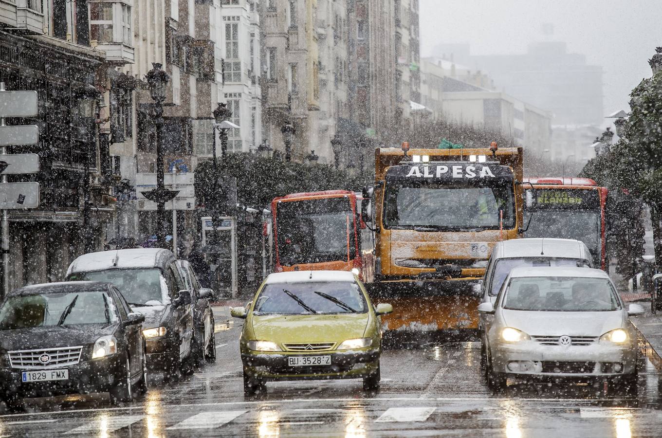 Varios vehículos transitan por una céntrica calle de la capital burgalesa que hoy amanecía bajo una intensa nevada. 