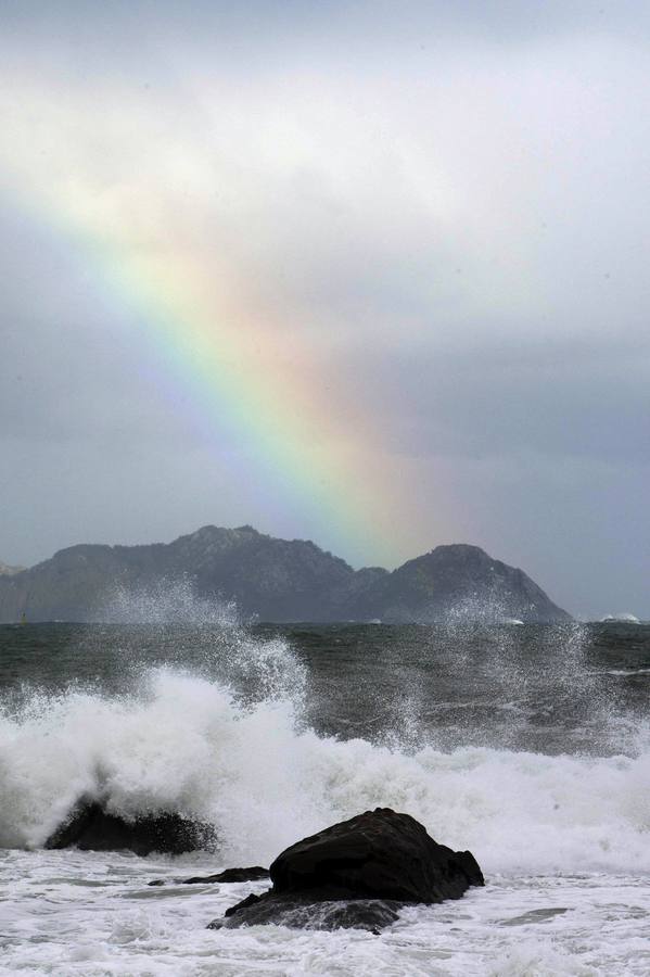 El temporal costero de viento y olas se mantiene en el litoral gallego. En la imagen, olas rompiendo bajo el arcoíris en Bayona (Pontevedra). 