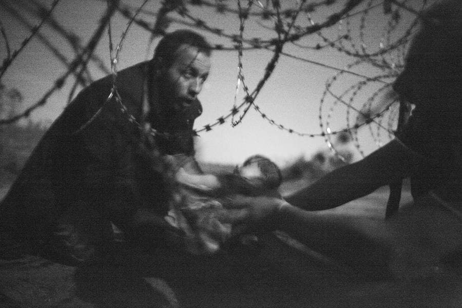 Fotografía ganadora del World Press Photo, del fotógrafo australiano Warren Richardson. La fotografía, en blanco y negro, muestra un hombre pasando a un bebe a través de la valla de alambre de espino en Roeszke, en la frontera entre Serbia y Hungría, el 28 de agosto de 2015