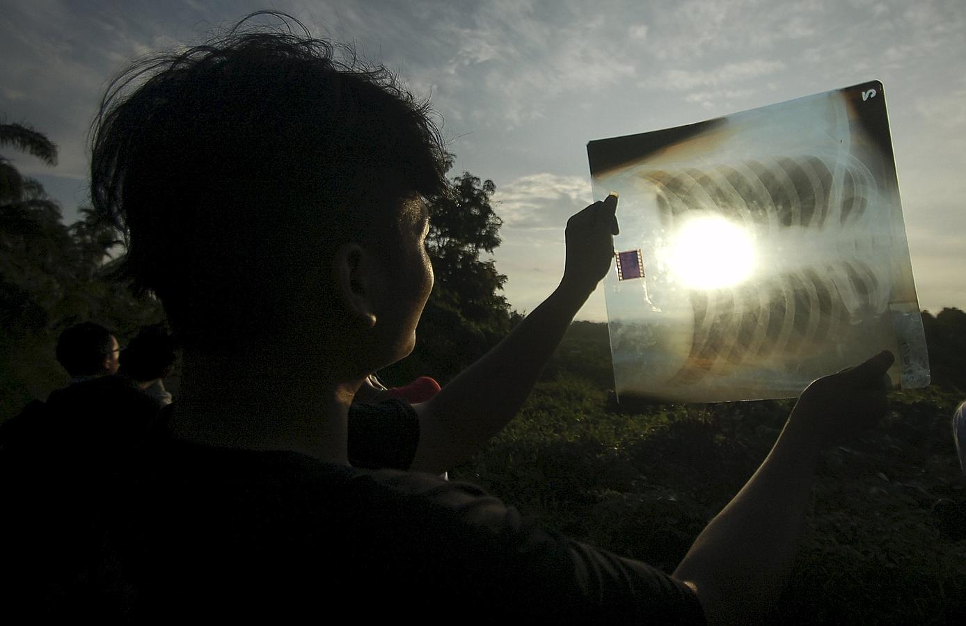 Una mujer observa el eclipse parcial de sol a través de una radiografía en Indonesia. 