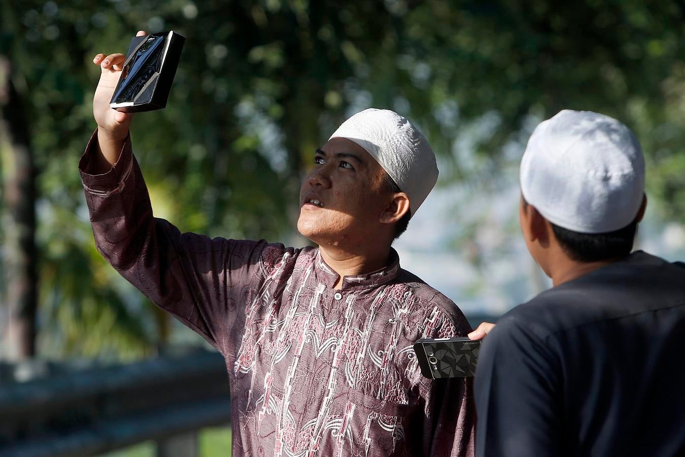 Un musulmán utiliza un filtro de película para ver el eclipse de sol en Indonesia. 