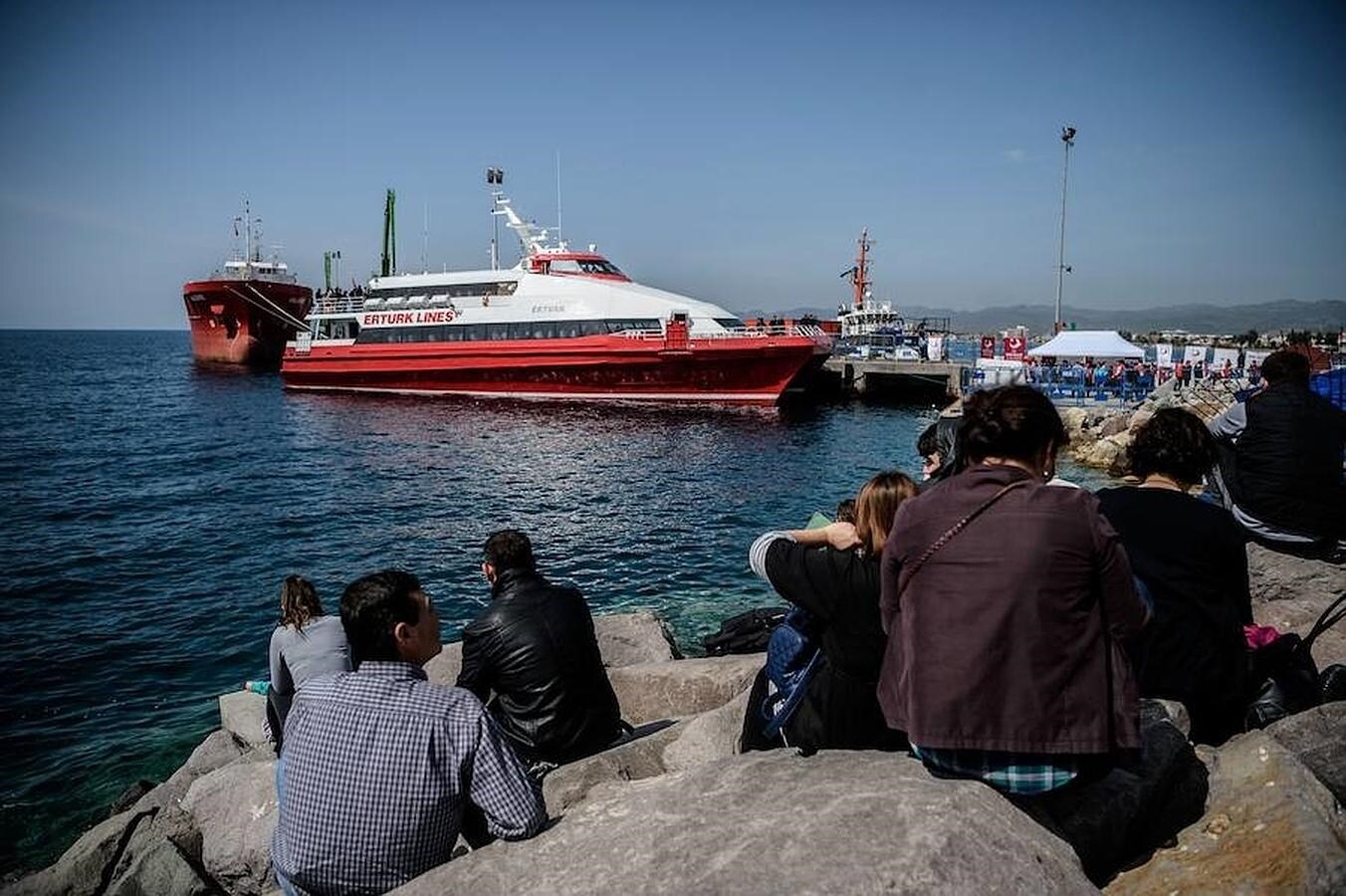 Un grupo de personas observa el ferry que trae a refugiados sirios al puerto turco de Dikili