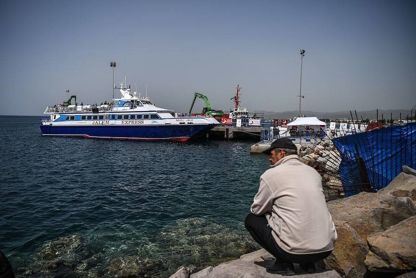 Un hombre observa como un ferry con bandera de Turquía traslada un segundo grupo de mgranets de Grecia a Turquía, donde desembarcará en el puerto de Dikili. 