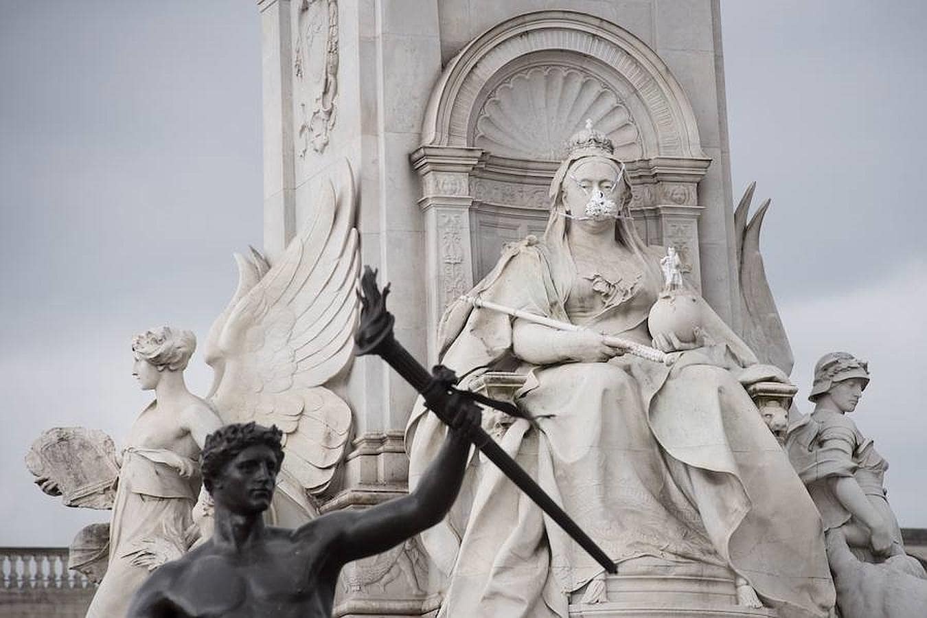 Miembros de Greenpeace ponen una mascarilla a la estatua de Reina Victoria. 
