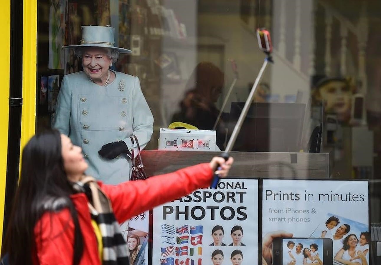 Una mujer se hace un selfie con una fotografía de Isabel II. 