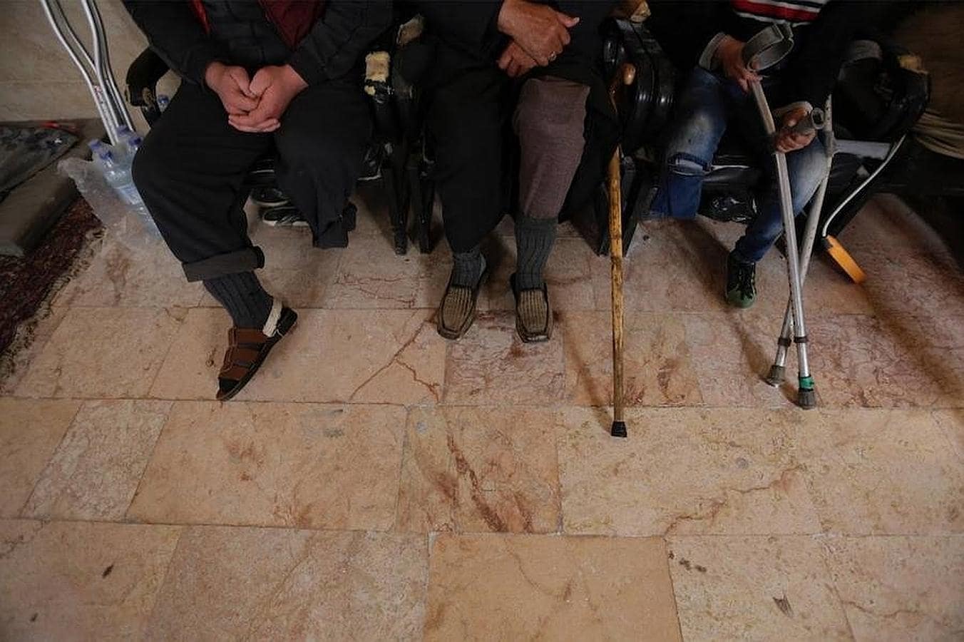 Hombres con sus piernas amputadas esperan para ser atendidos por la clínica ambulante de Khamis y Khlouf