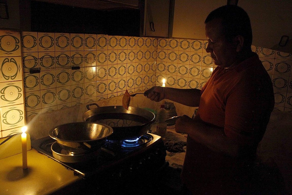 Un hombre cocina con velas por el apagón de luz en San Cristóbal, Venezuela. 