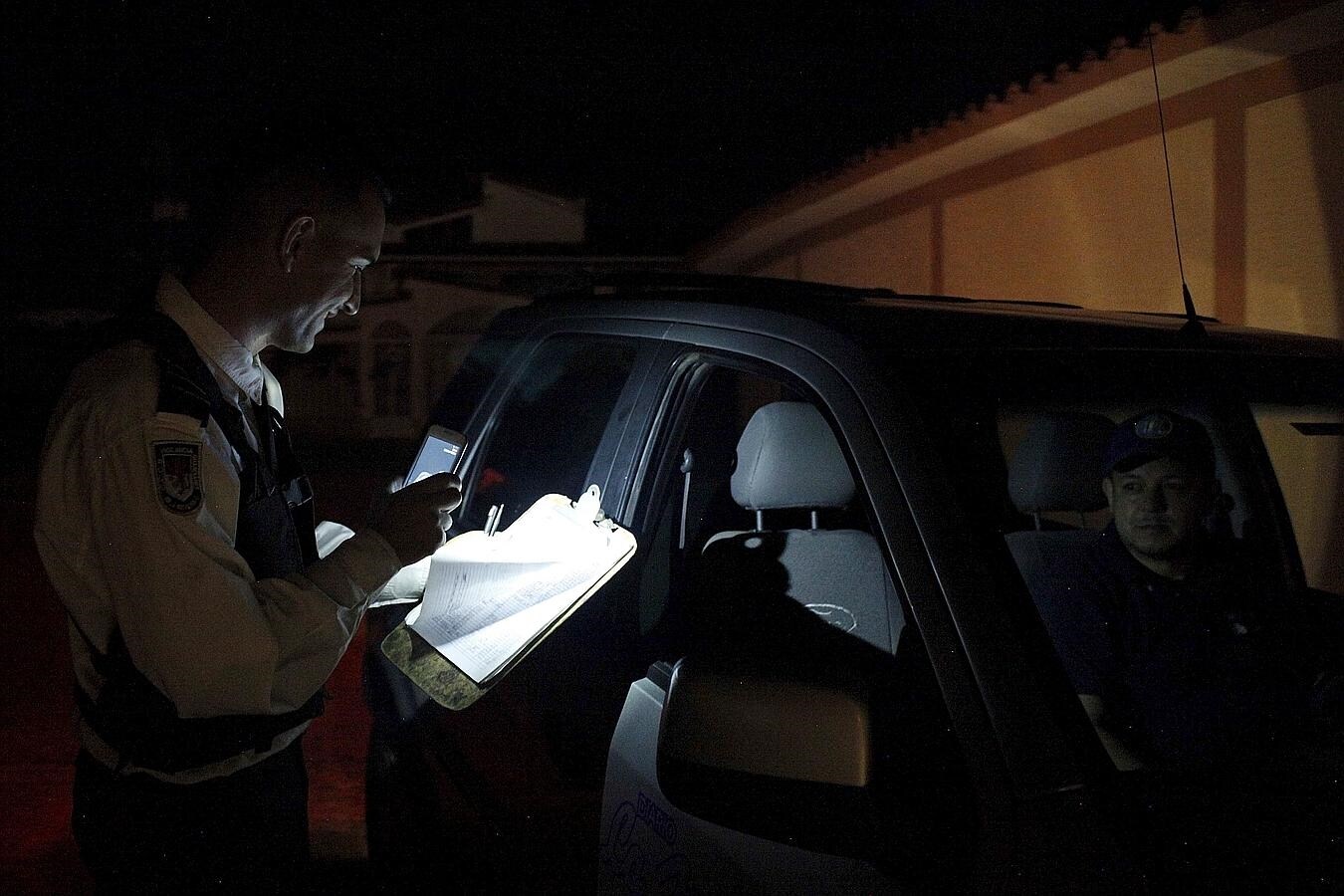 Un vigilante utiliza su teléfono móvil para iluminar un papel durante el apagón de luz en San Cristóbal, Venezuela
