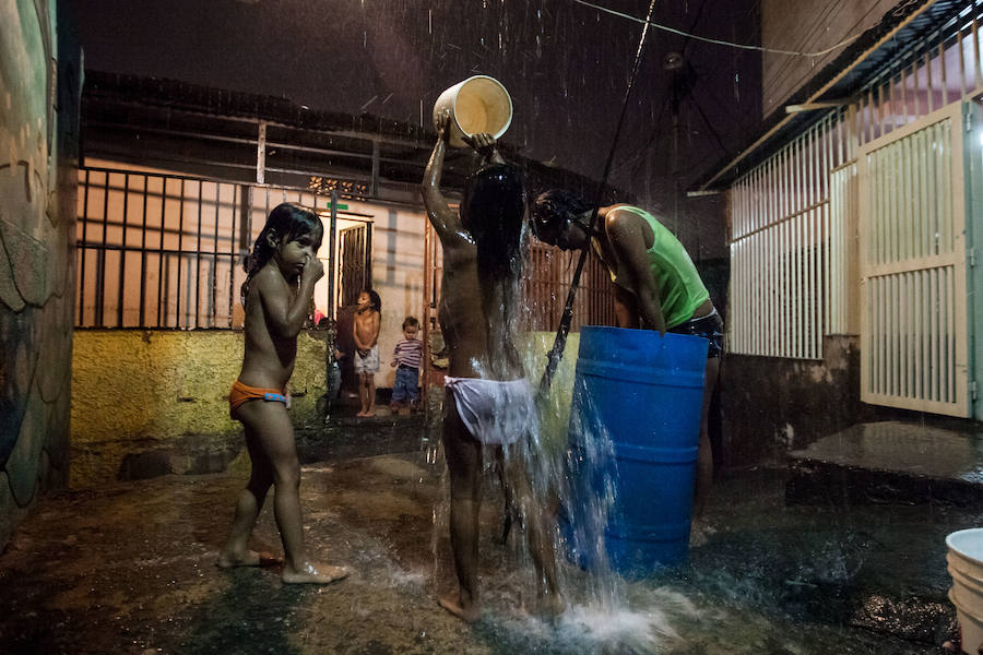 Unos niños se bañan con agua de lluvia, por los cortes de agua a causa de la sequía que sufre Venezuela. El baño improvisado se produjo en un callejón de La Bombilla, dentro de la inmensa favela de Petare, en Caracas. 