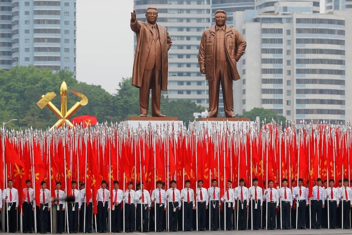 Estudiantes con banderas del Partido de los Trabajadores (PTC), bajo las estatuas de los ex líderes coreanos Kim II Sung y Kim Jong II, al comienzo del desfile. 