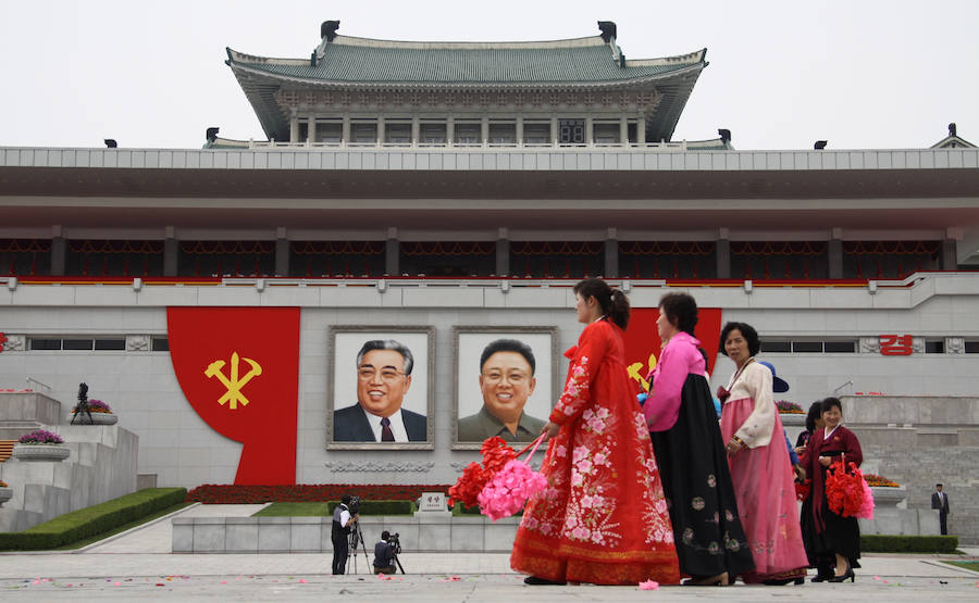 Atavidas con el traje tradicional, varias mujeres pasan bajo los retratos de los líderes en la Plaza de Kim Il-sung, en Pyongyang. 