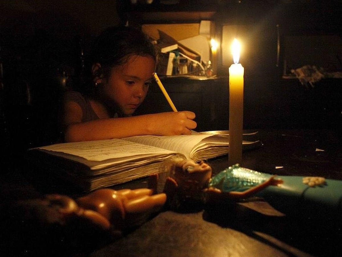 Las últimas restricciones han tenido que ver con los cortes de luz eléctrica durante varias horas al día. En la imagen, una niña estudia alumbrada por una vela. 
