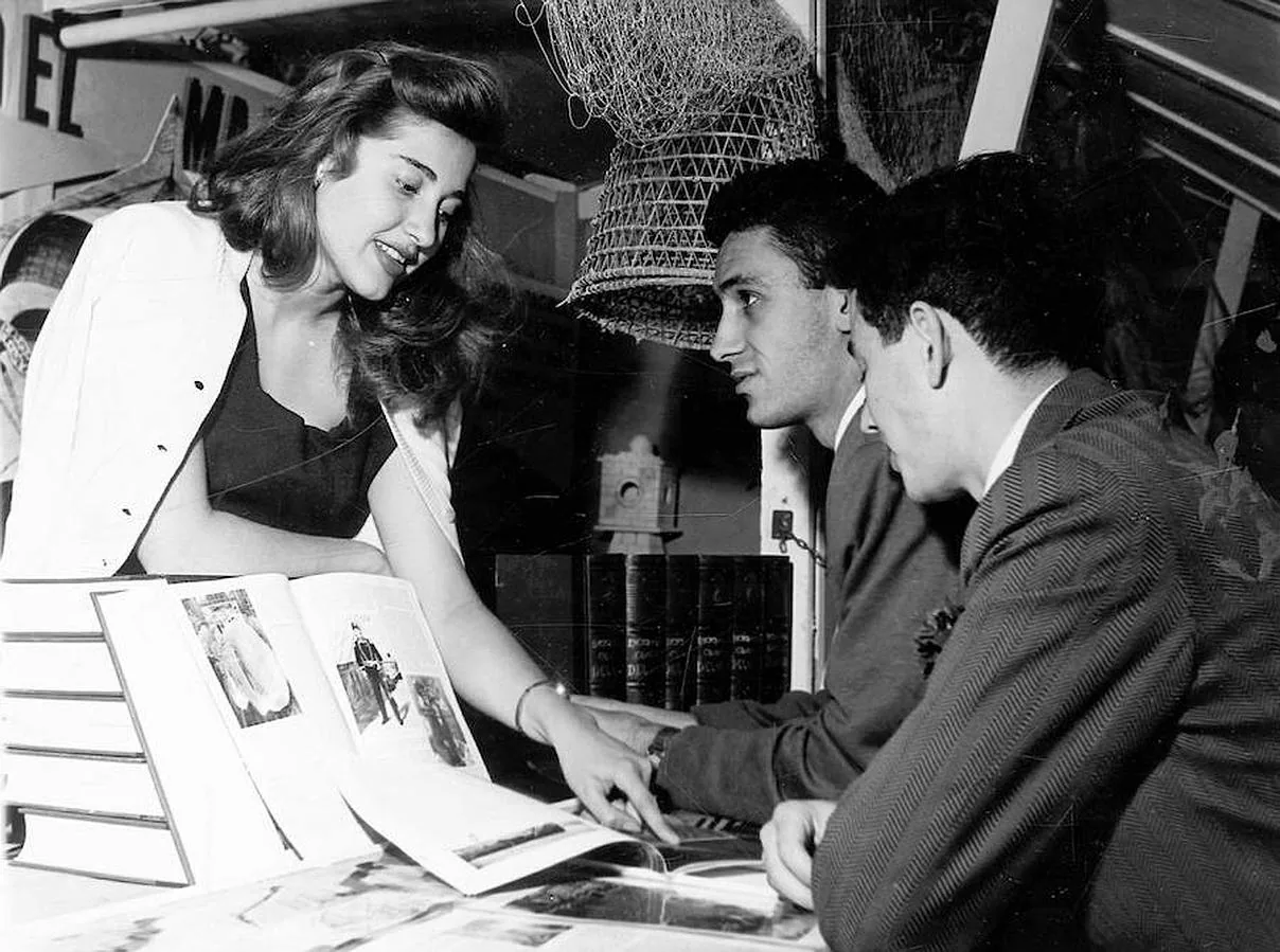 Una joven muestra un libro a dos hombres en 1957
