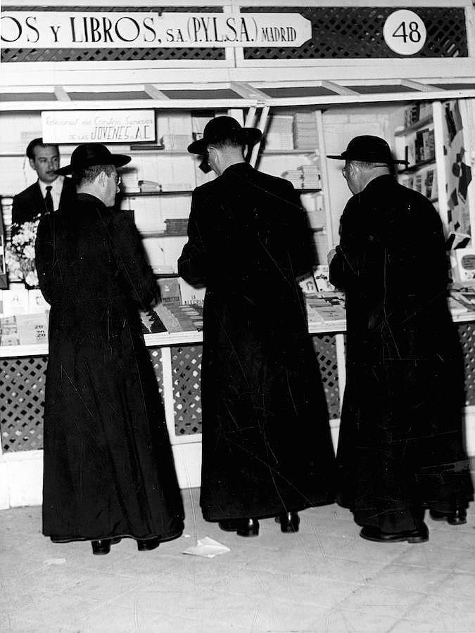 Tres religiosos miran libros en una de las casetas en 1957